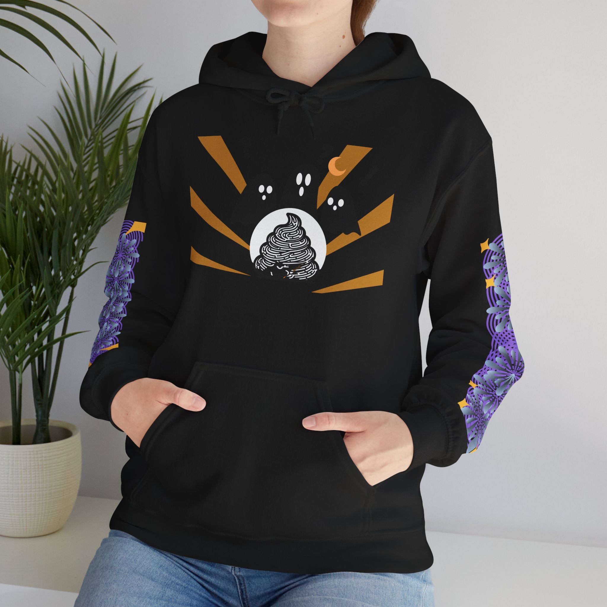 Person wearing a black hoodie with a unique design, standing indoors with a plant in the background.