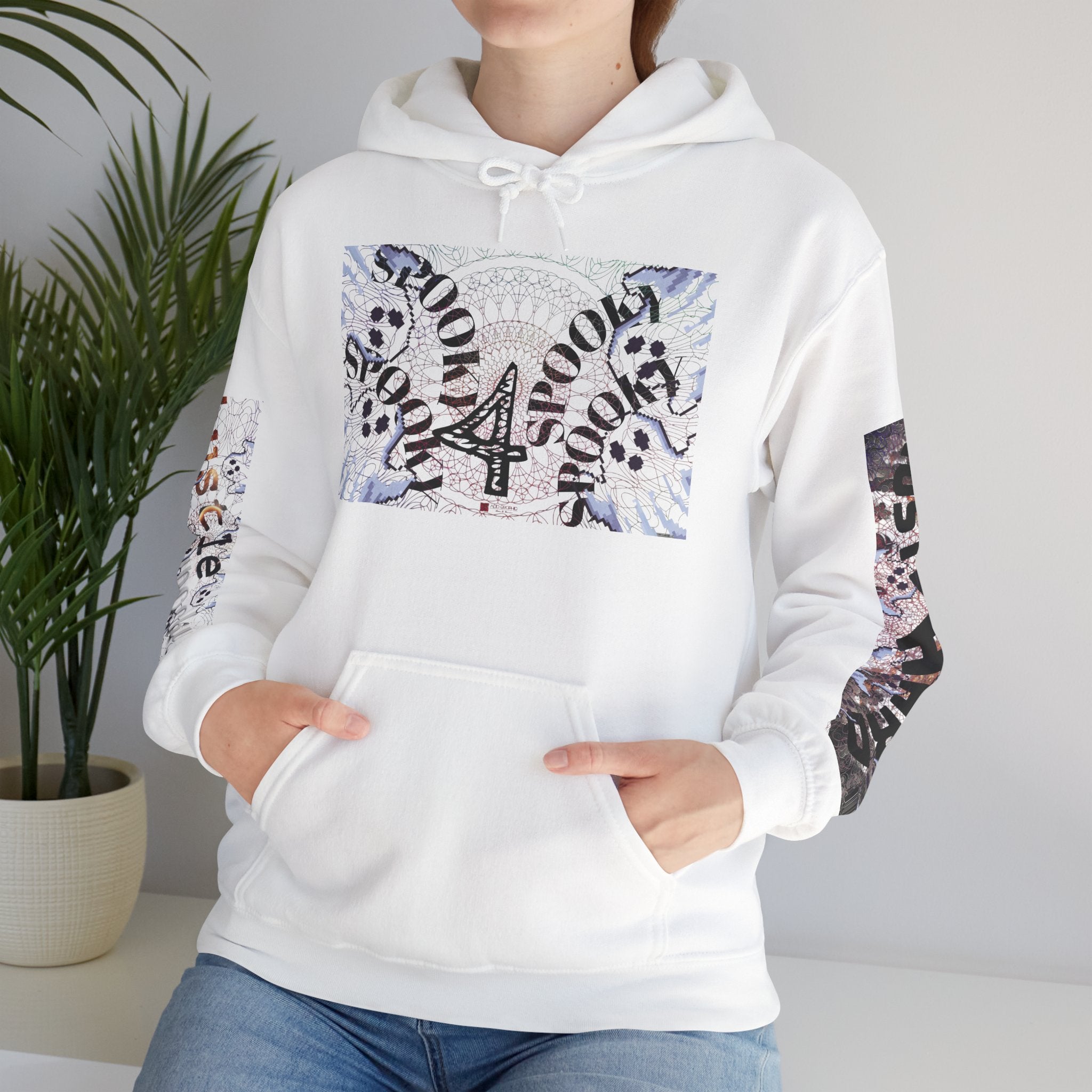 White hoodie with graphic designs worn by a person, with a plant in the background