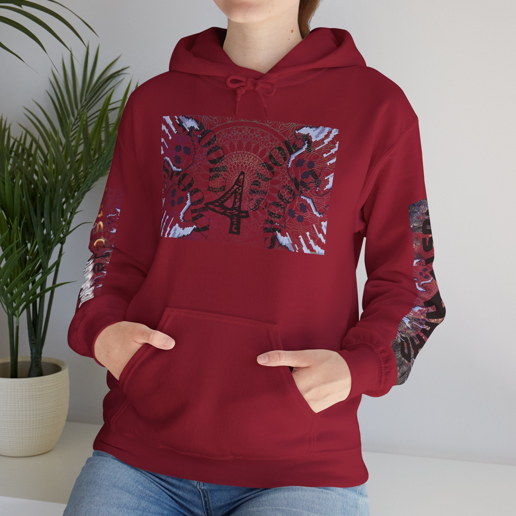 Person wearing a red hoodie with graphic designs, standing indoors next to a plant.