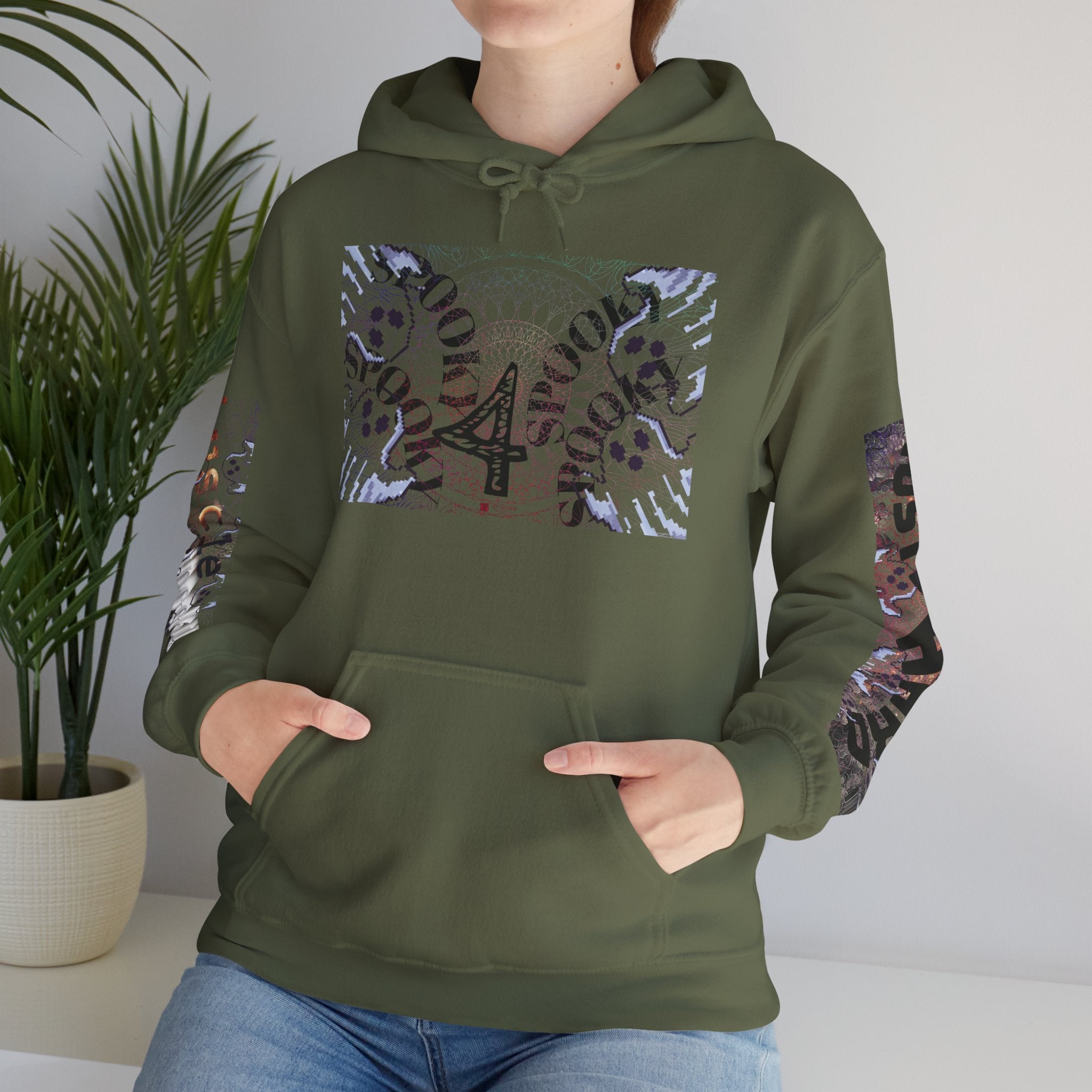 Person wearing a green hoodie with decorative sleeves in a room with a plant.